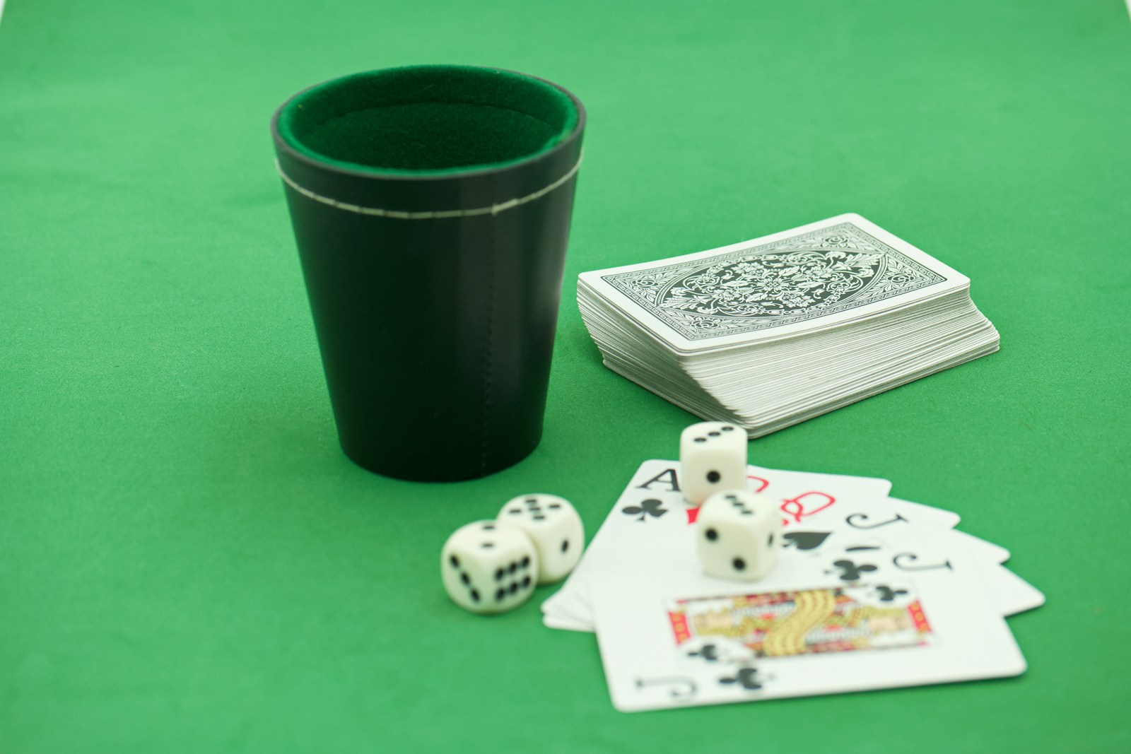 a green table topped with playing cards and dice
